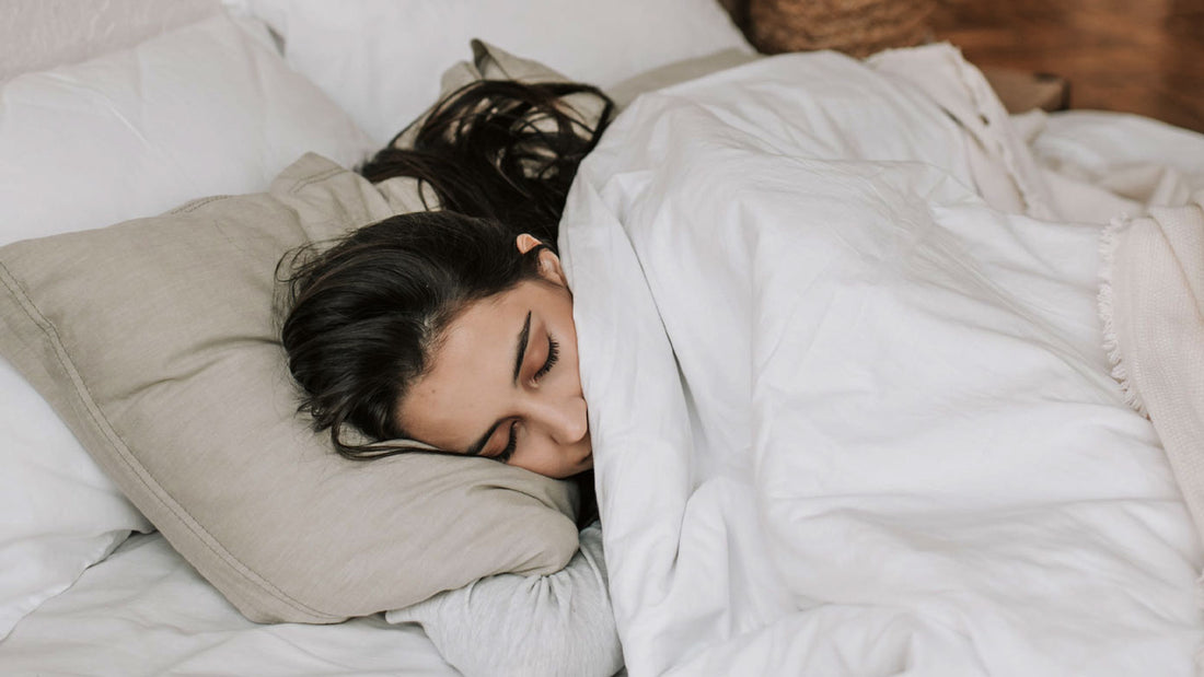 Vrouw ligt onder de dekens in bed