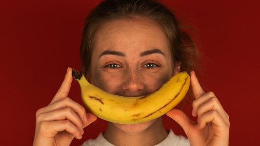 Vrouw lacht met een banaan voor haar gezicht