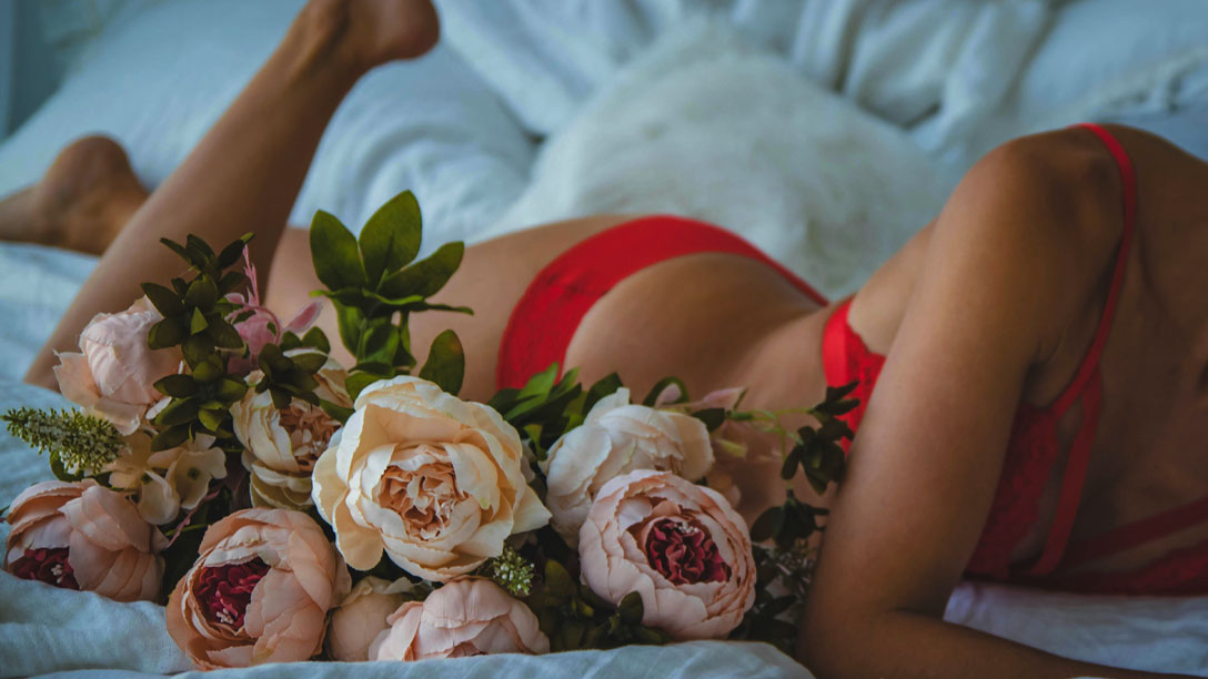 Vrouw in rode lingerie naast een bos rozen