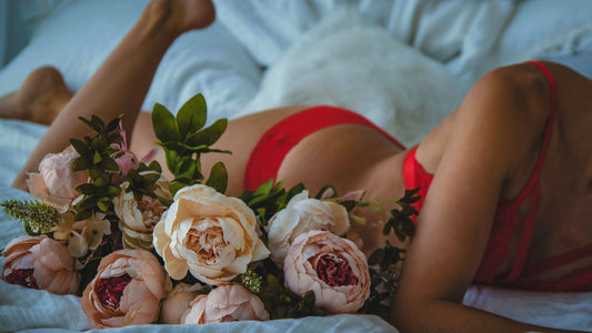 Vrouw in rode lingerie naast een bos rozen