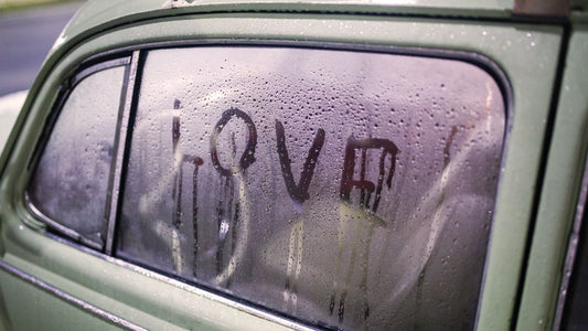 Autoruit beslagen met de tekst "Love" erop geschreven