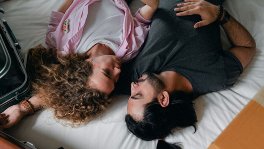 Een koppel in bed met een vragende blik naar elkaar